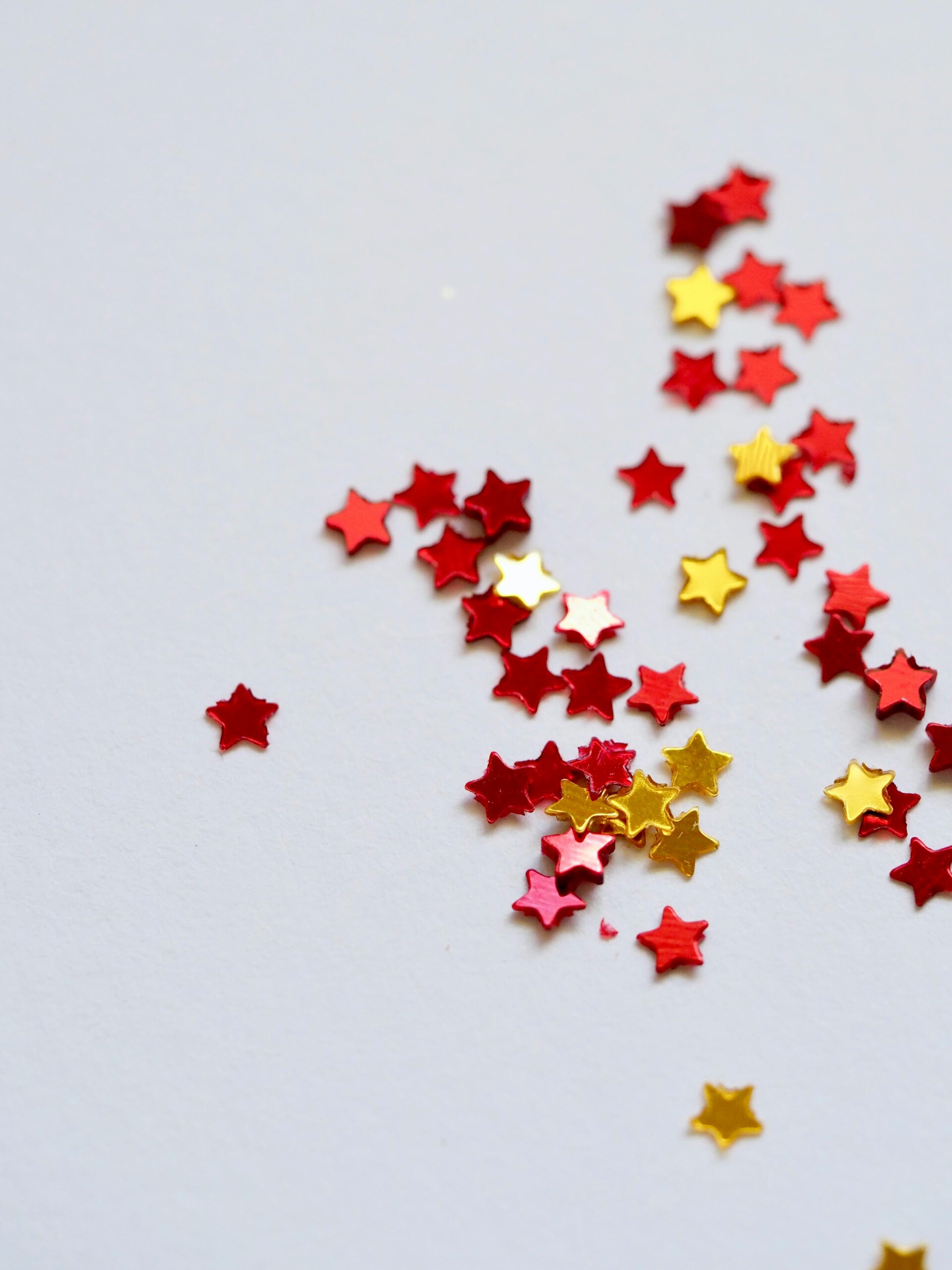 Photo of red and gold star-shaped confetti on white background.