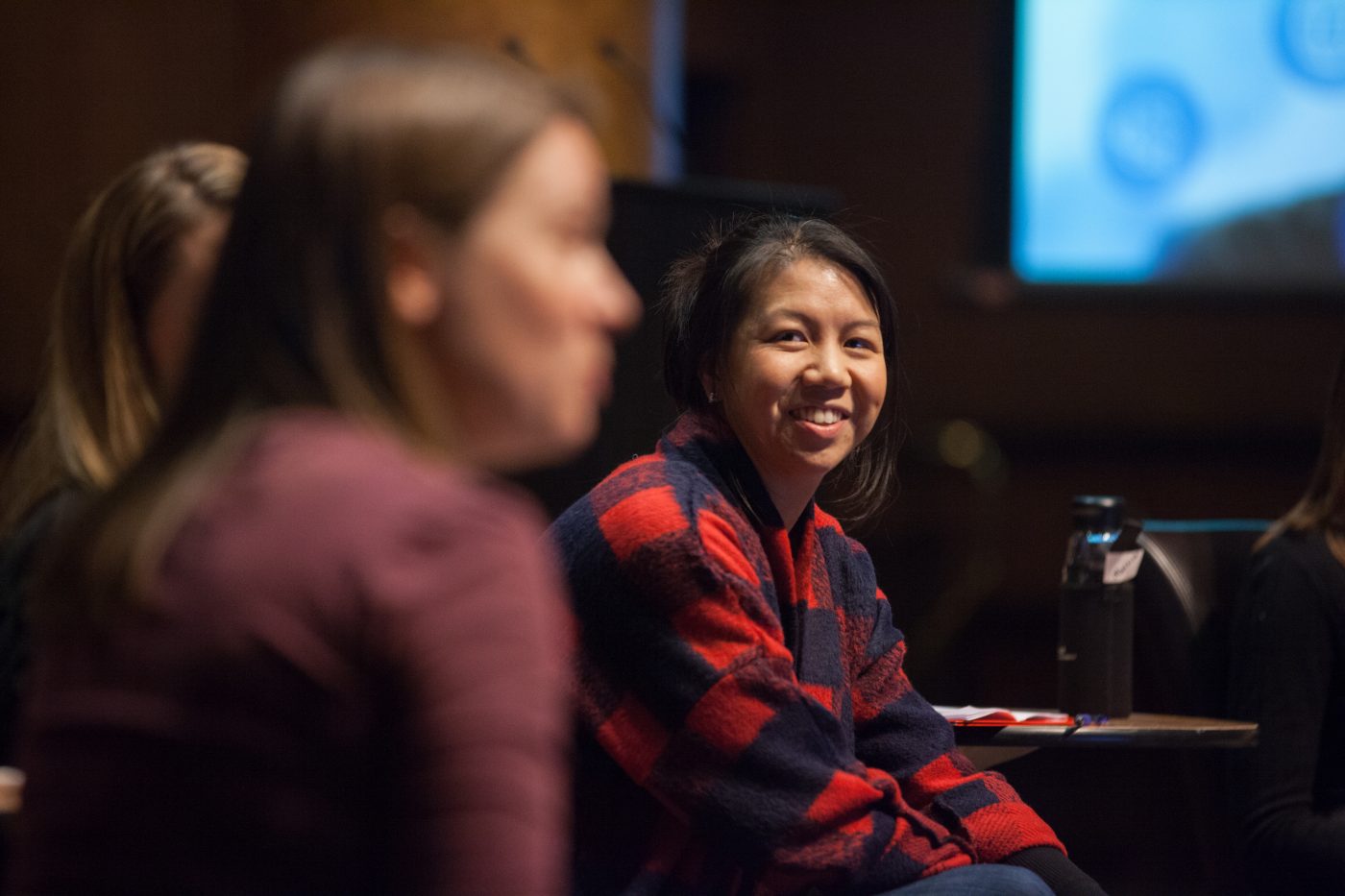 A woman scientist smiles during a panel discussion on stage.