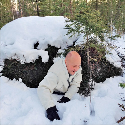 A man shows the size of an uninhabited bear hibernating (Lapland, Sweden)