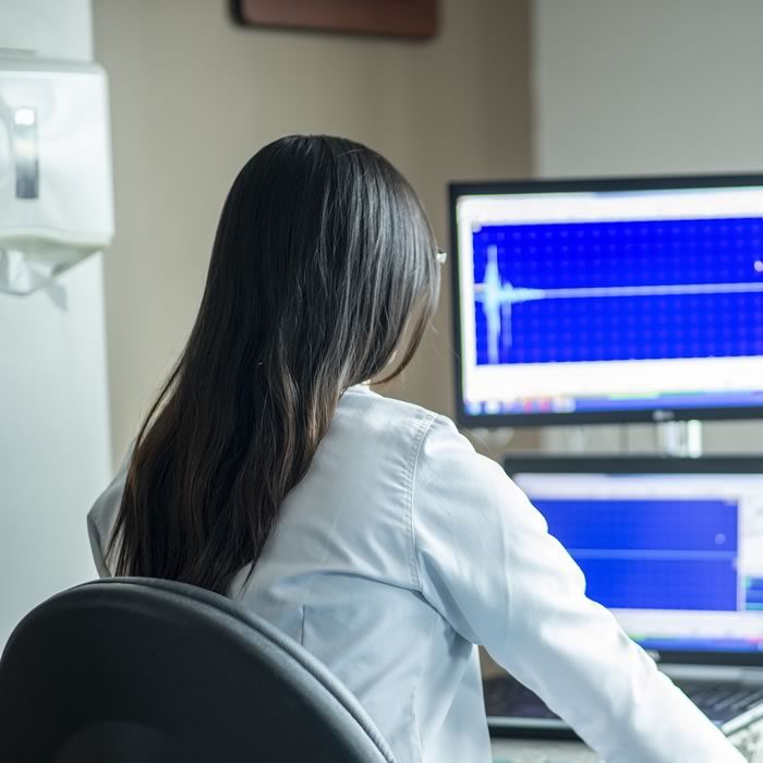 Woman in lab coat at computer screen