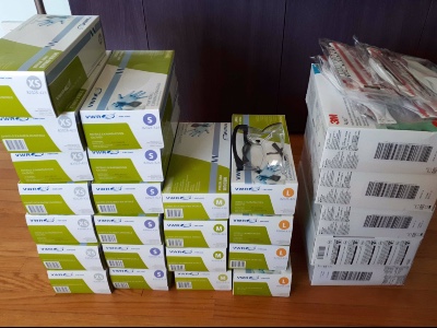 Boxes of nitrile gloves and N95 masks in a pile to be donated.