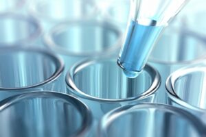 Several test tubes and a drop of liquid at the tip of a pipette.