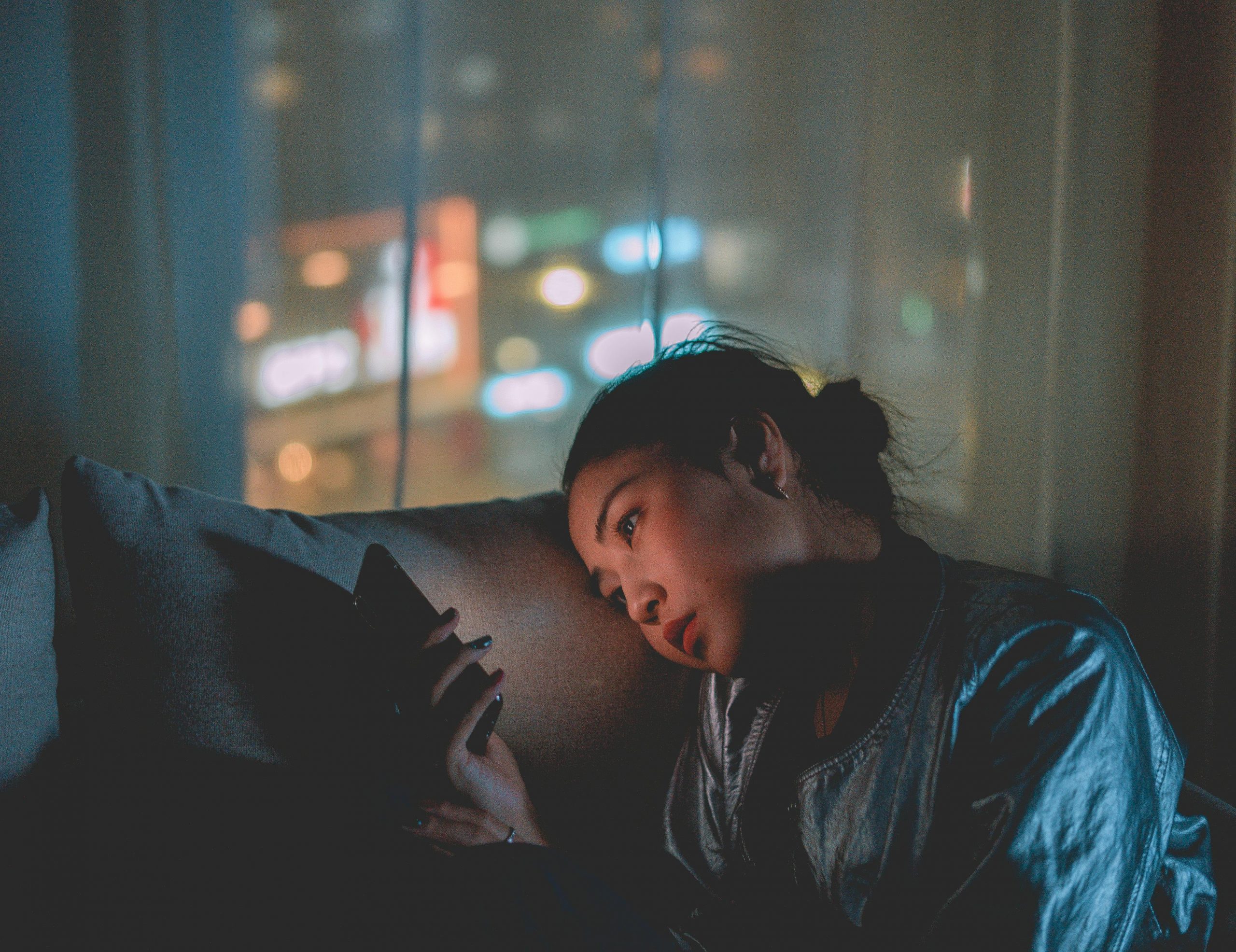 young woman looking at phone on couch in the dark